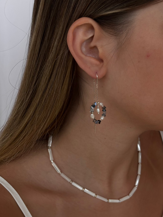 עגיל תלוי עשוי כסף 925 או כסף בציפוי זהב עם תליון עגול של חרוזי זכוכית, פנינים וחרוזיים מלבניים בציפוי כסף או זהב עם תליון מרכזי של פנינה מתנדנדת.