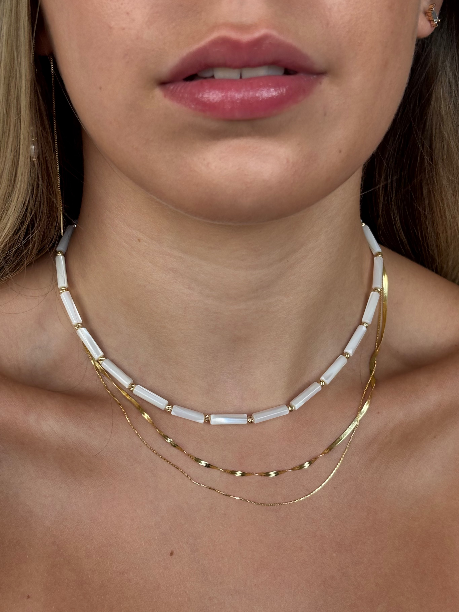 שרשראות עדינות בשילוב חרוזי פנינה לבנים וציפוי זהב סביב הצוואר